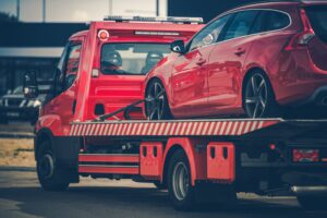 Red Broken Car on a Red Towing Truck. Closeup Photo. Vehicle Mechanical Problem on the Road.